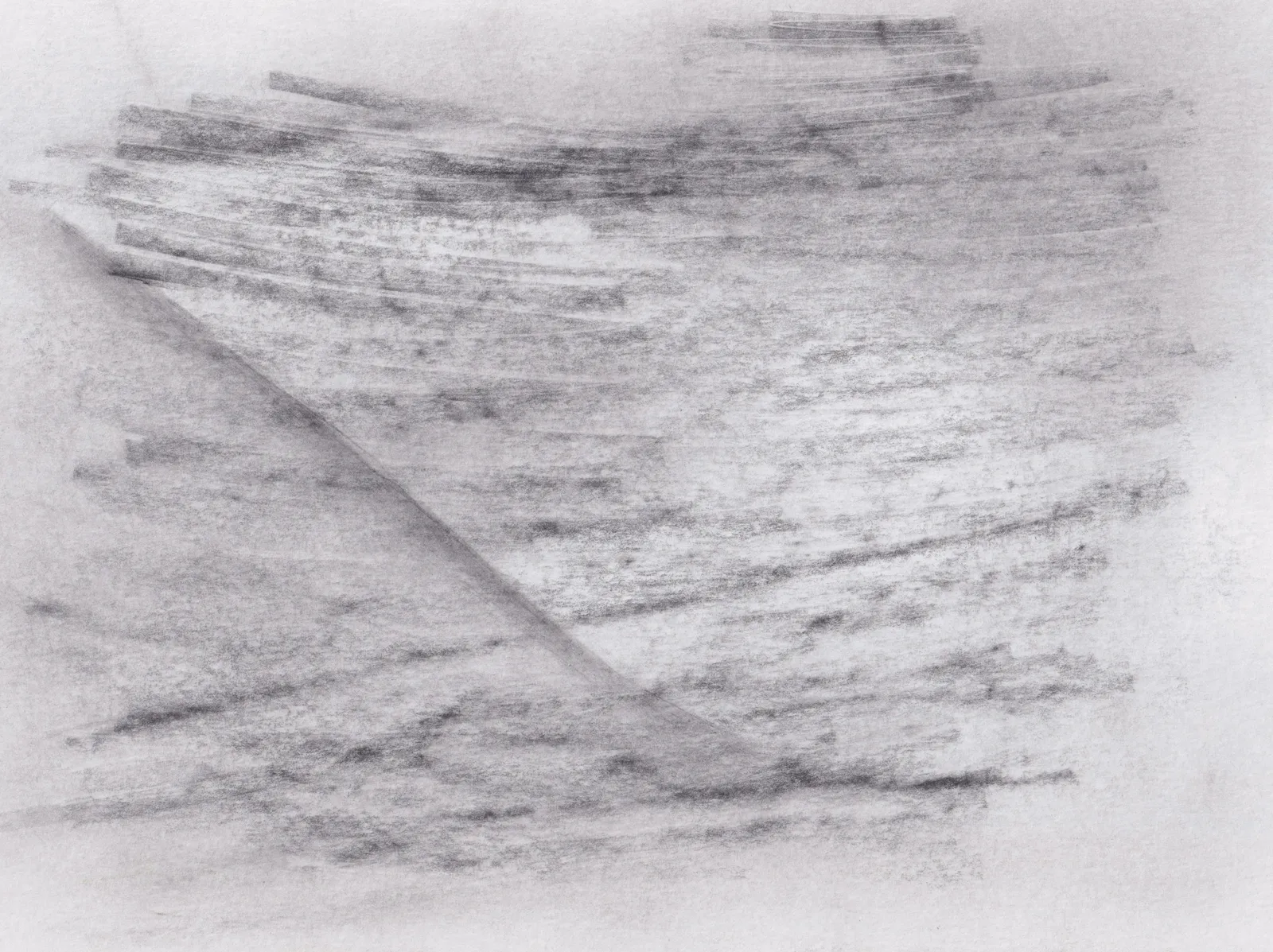 Soft graphite strokes running across white paper, cut by a single diagonal crease of tone