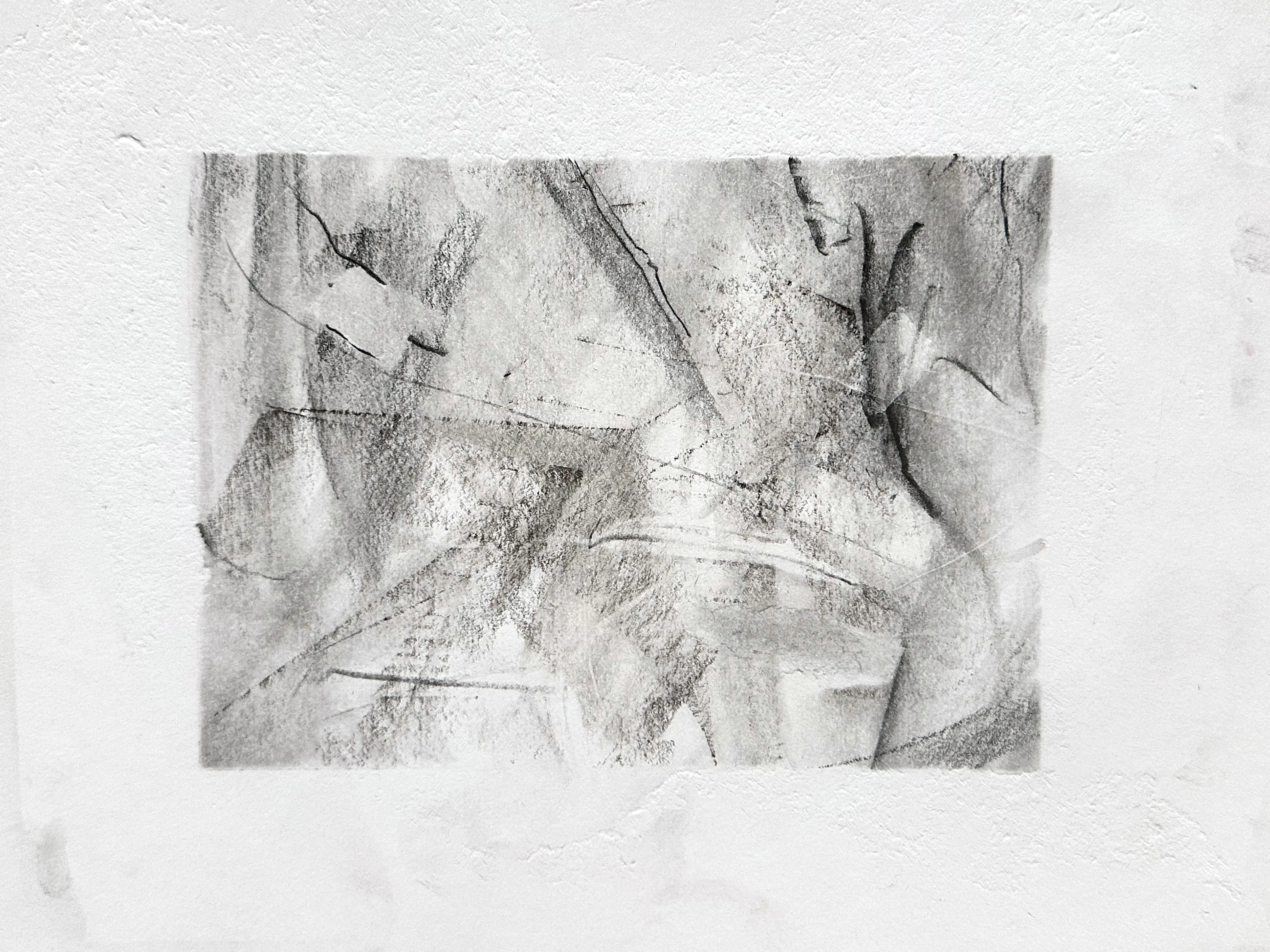 Wide graphite drawing on white paper: overlapping smudged planes crossed by sharp diagonal lines, with dark curved strokes like wings along the right side