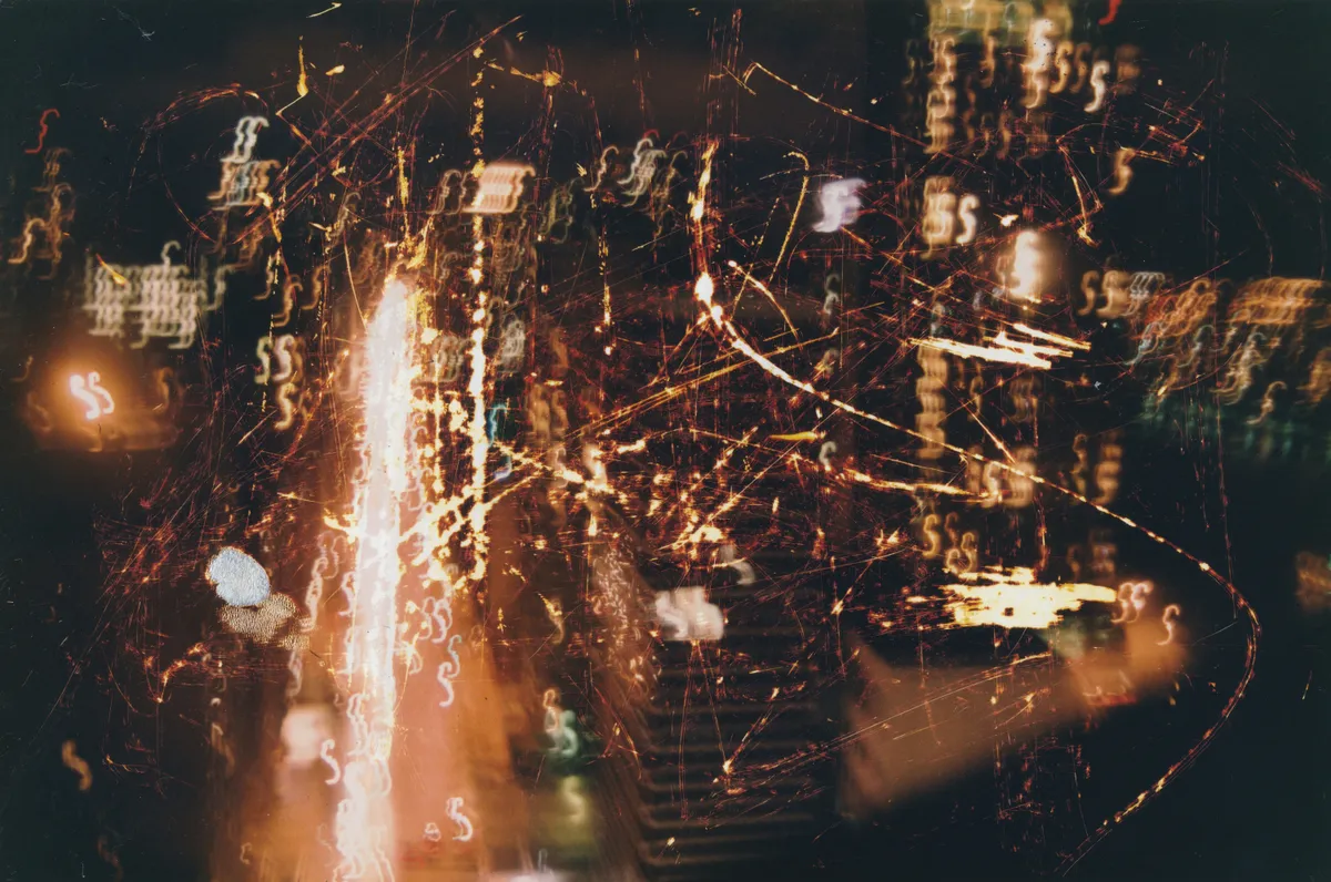 Night photograph of city lights blurred into streaks and squiggles, scratched with fine orange lines